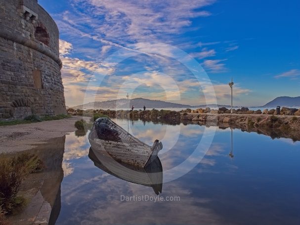 Un bateau à l'arrêt se reflète dans l'eau calme près d'une vieille forteresse.