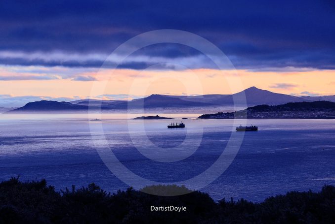Coucher de soleil sur un paysage marin avec des bateaux et des collines à l'horizon.