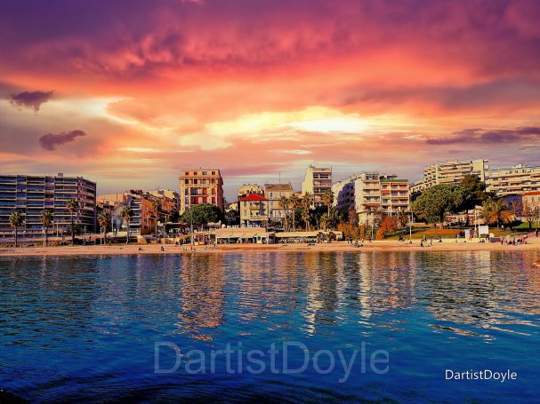 Coucher de soleil coloré sur une plage urbaine avec des bâtiments en arrière-plan.