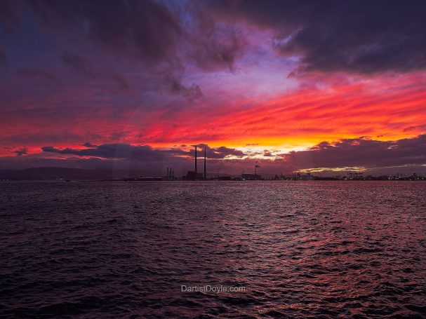 Coucher de soleil coloré sur l'océan, avec des nuages colorés et un ciel vibrant.