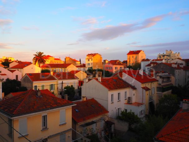 Vue panoramique de maisons avec toits rouges sous un ciel au crépuscule.