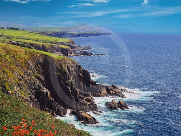 Vaste paysage côtier avec des falaises verdoyantes bordant une mer turquoise.