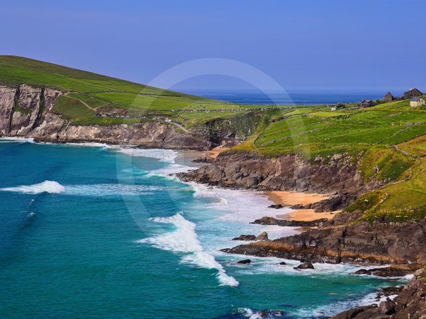 Côte sauvage avec des vagues, falaises et collines verdoyantes au bord de la mer.