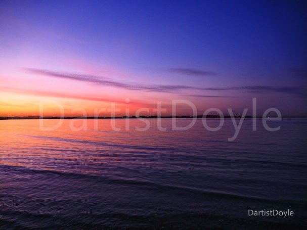 Coucher de soleil sur l'eau avec des nuances de violet et d'orange.